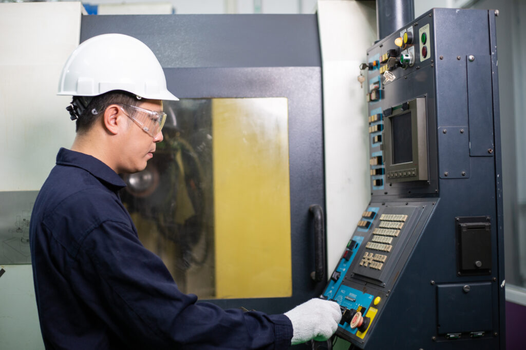 Asian male engineer foreman controlling industry metal machine a