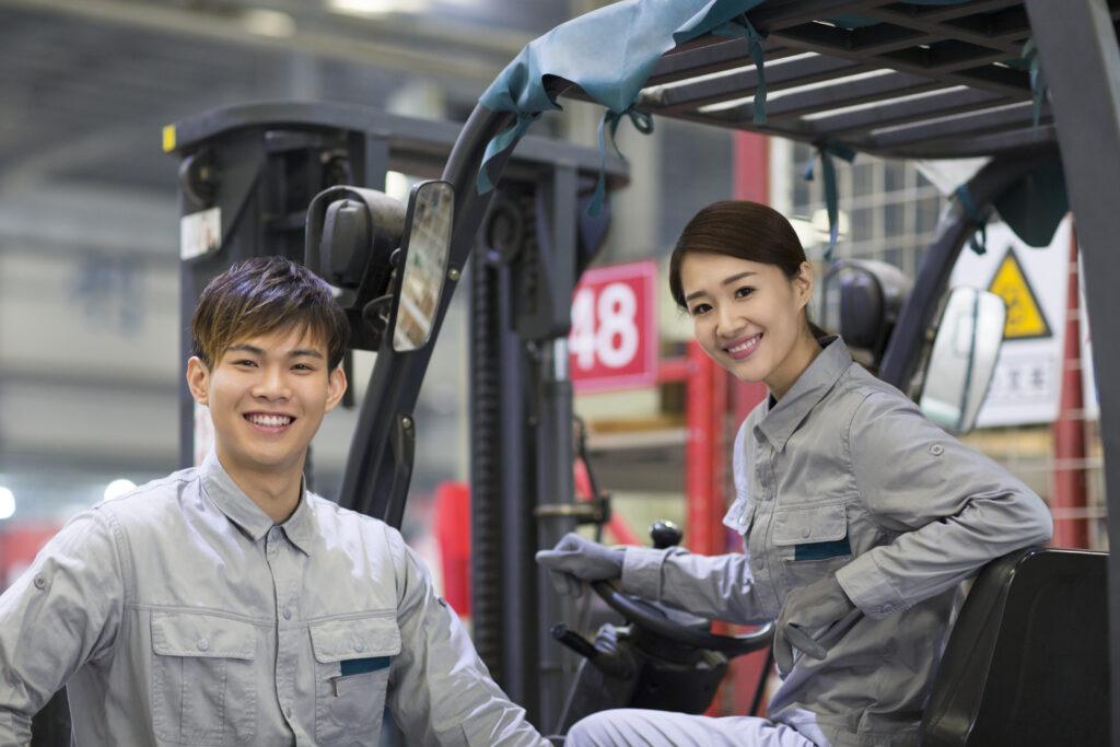 Confident chinese workers driving forklift in the factory